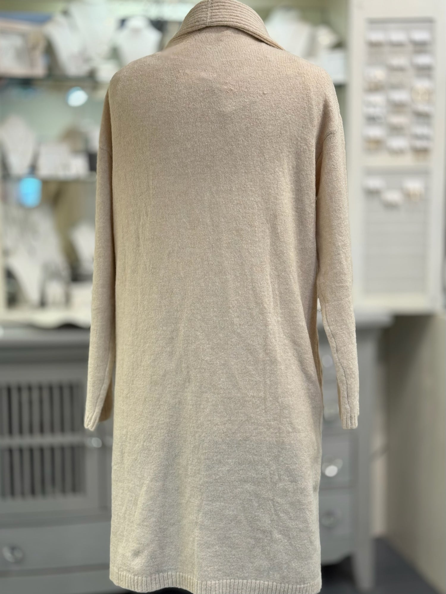 Beige sweater dress on a mannequin in a store setting