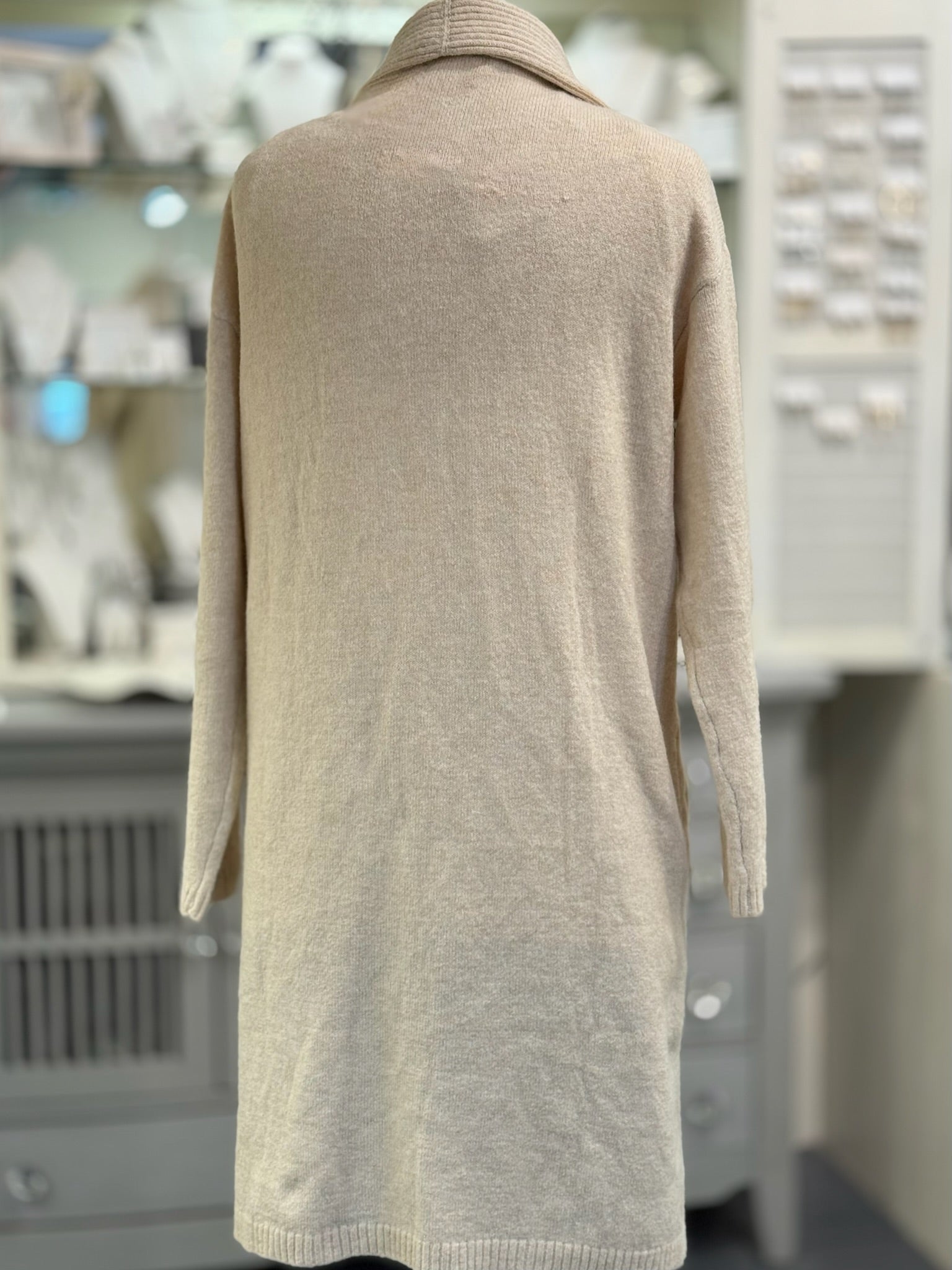 Beige sweater dress on a mannequin in a store setting