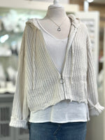Knitted cardigan over a white shirt on a mannequin with a blurred indoor background
