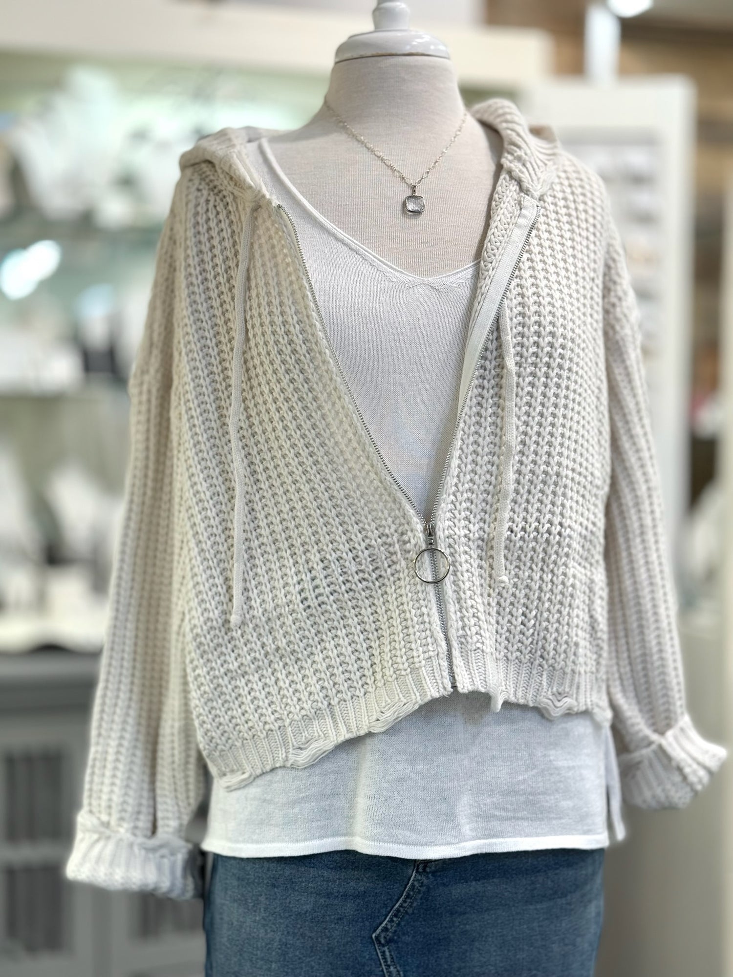 Knitted cardigan over a white shirt on a mannequin with a blurred indoor background