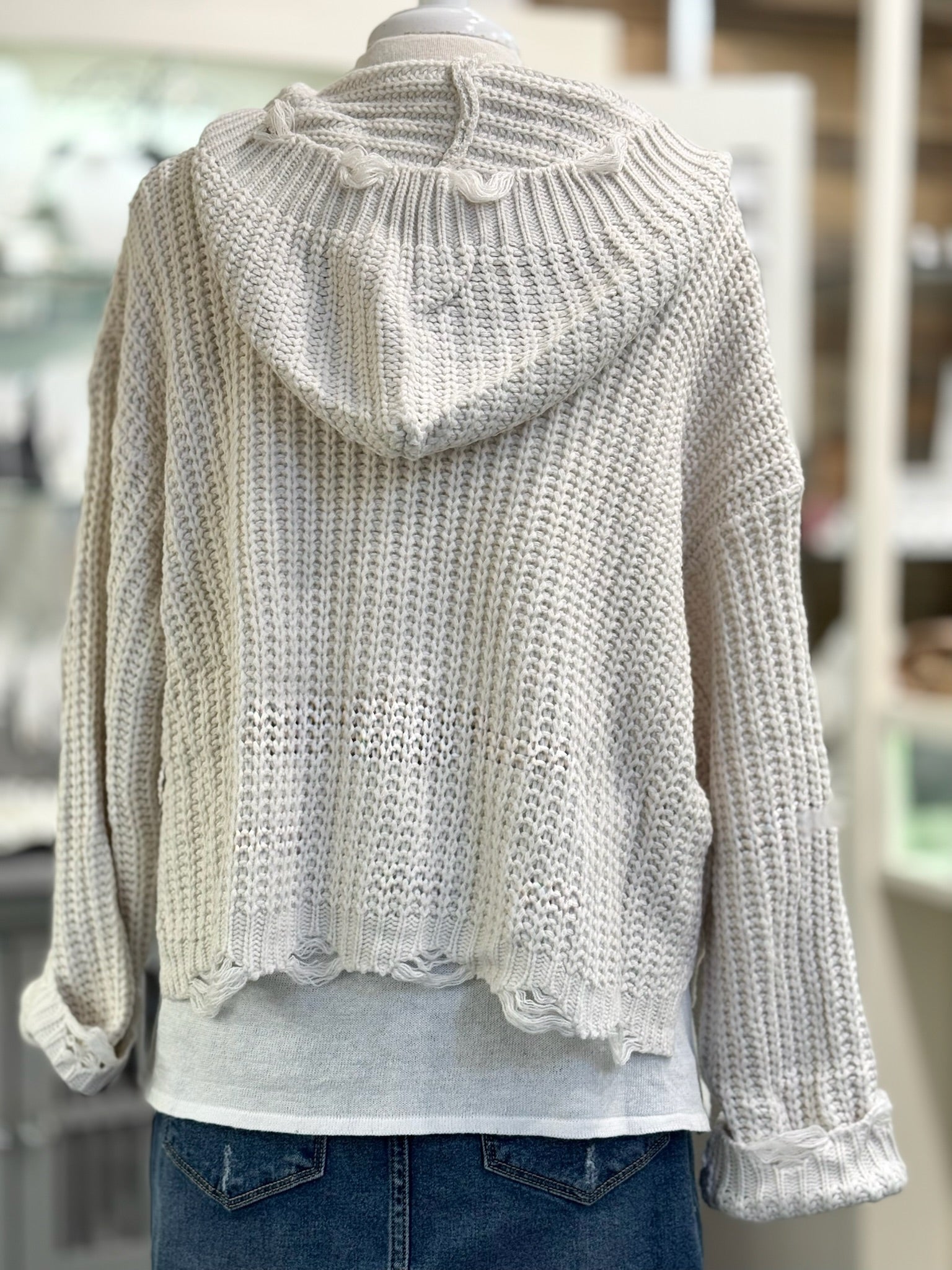 Knitted sweater with a hood on a mannequin against a blurred indoor background