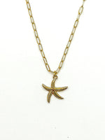 Gold starfish pendant necklace on a white background