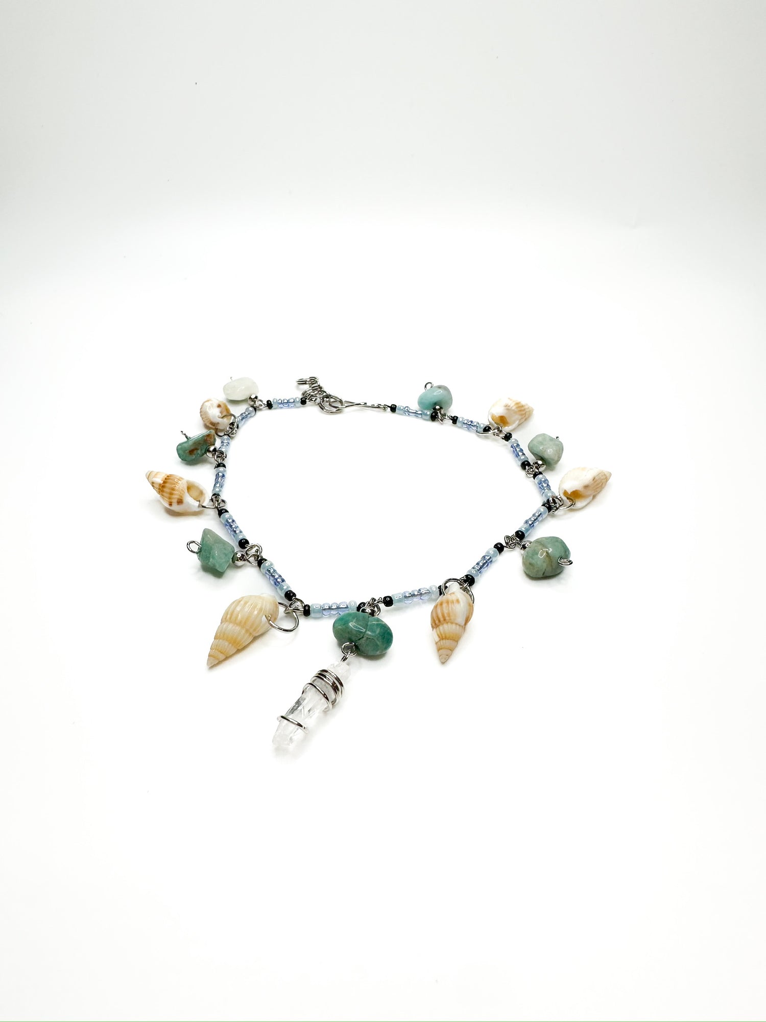 Beaded anklet with hanging seashells, green gemstones, and a clear quartz charm