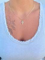 Gold cross necklace with clear stones being worn 