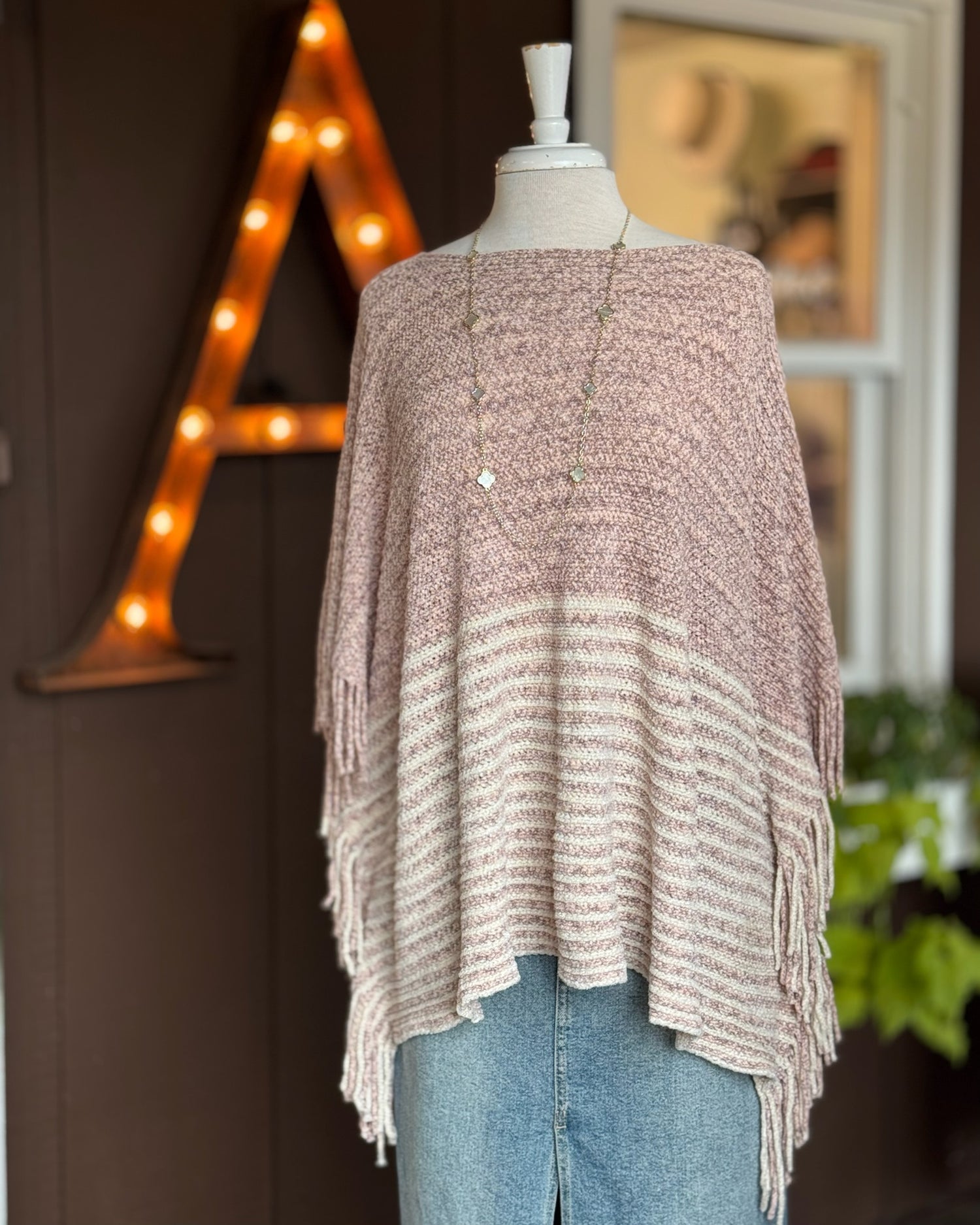 Ardor Boutique Nisswa MN Knitted poncho on a mannequin with a blurred background