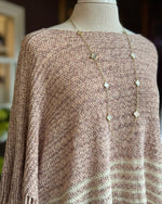 Mannequin wearing a brown knitted sweater with a long necklace.