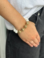 Bracelet with gold and white beads on a wrist