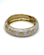 Wide enamel bangle with gold floral detailing and hinge clasp"