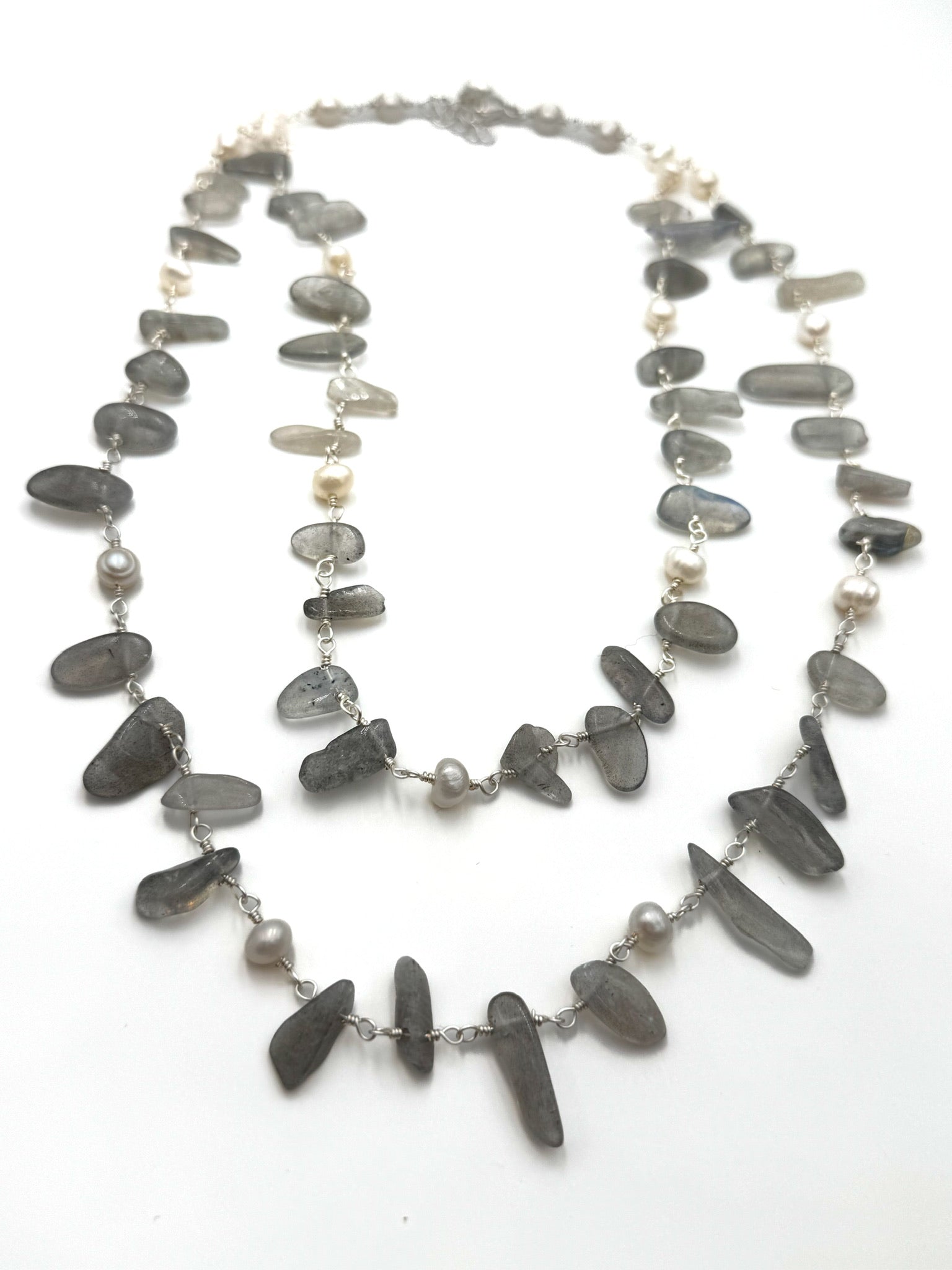 grey stone and pearl double layered necklace on a white background.