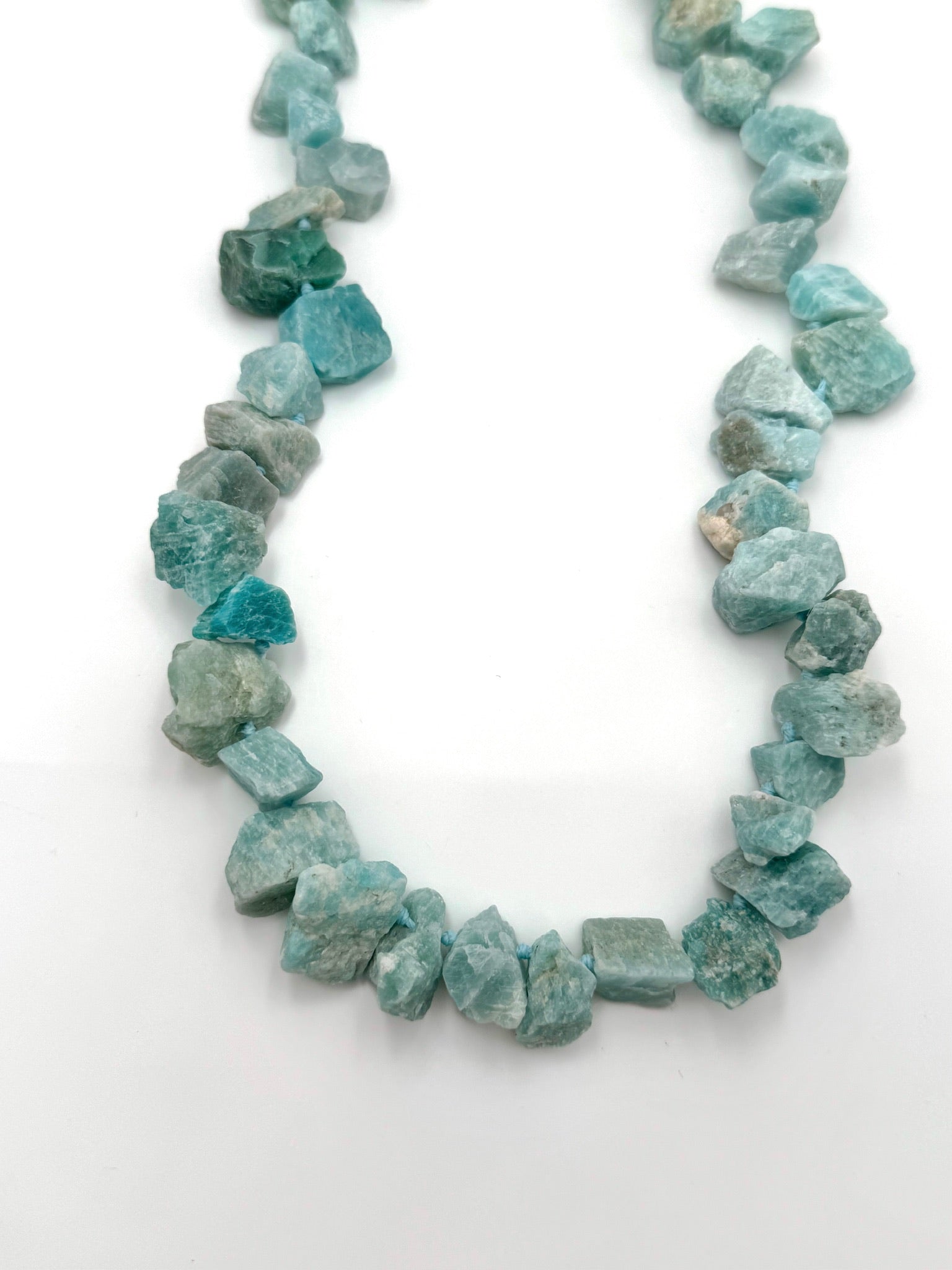 Necklace made of blue-green gemstones on a white background