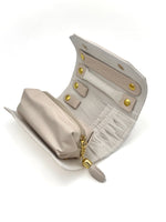 Open pink jewelry travel roll showing zippered pouch, necklace snaps, and earring straps.