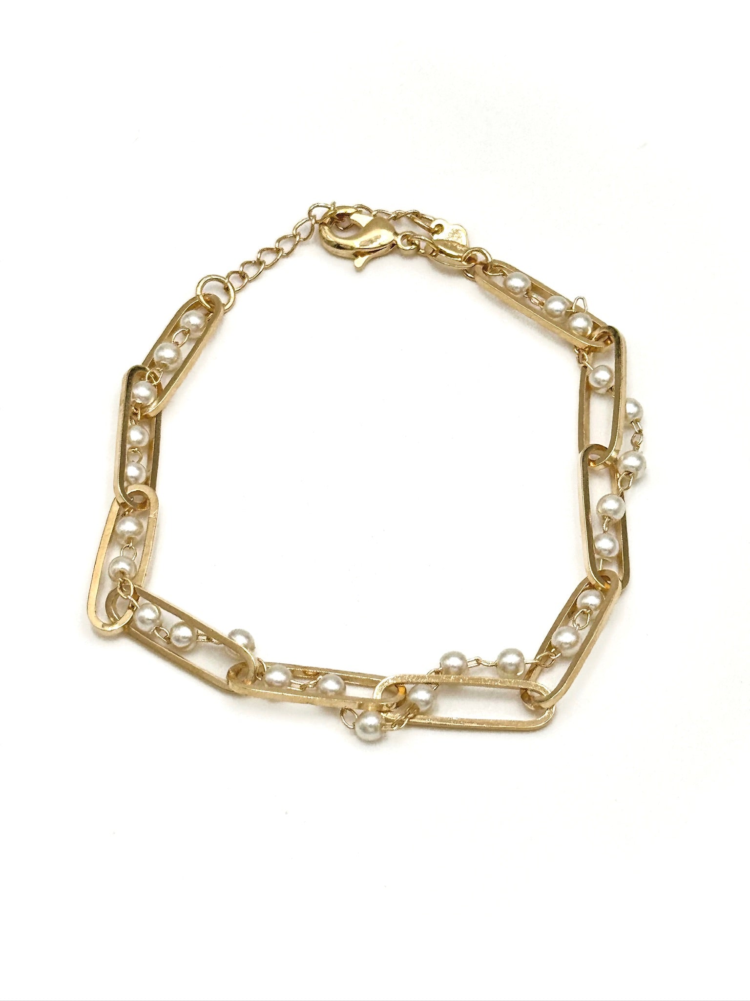 Gold bracelet with pearl accents on a white background