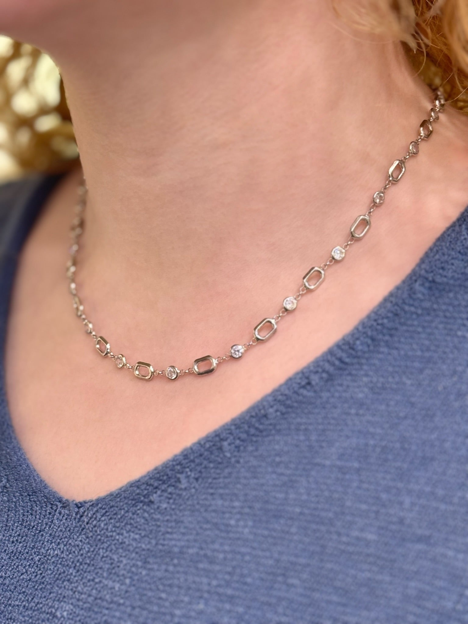 Necklace with small diamonds on a person wearing a blue top