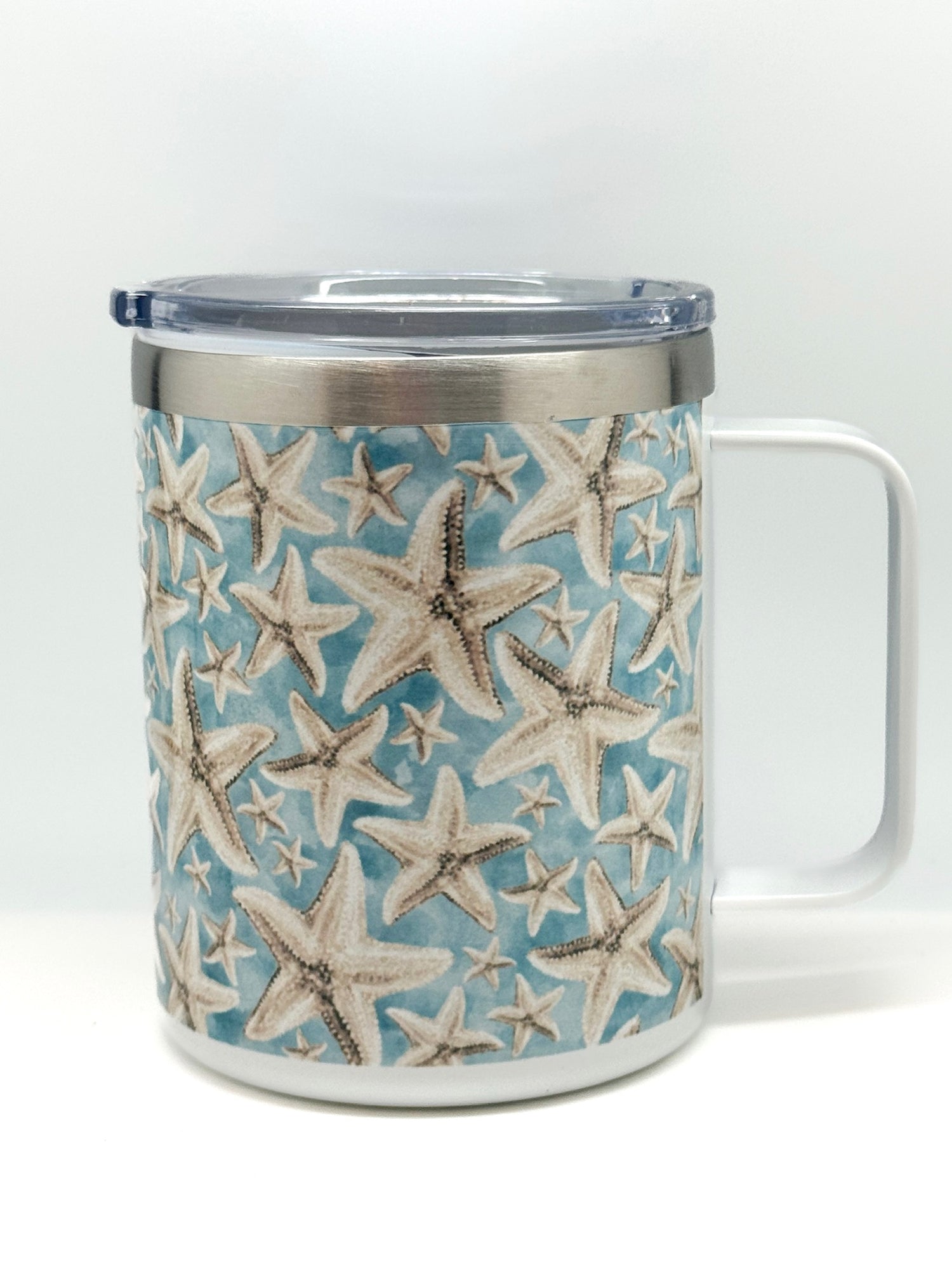 Travel mug with handle and clear lid, featuring sandy starfish pattern on a blue background
