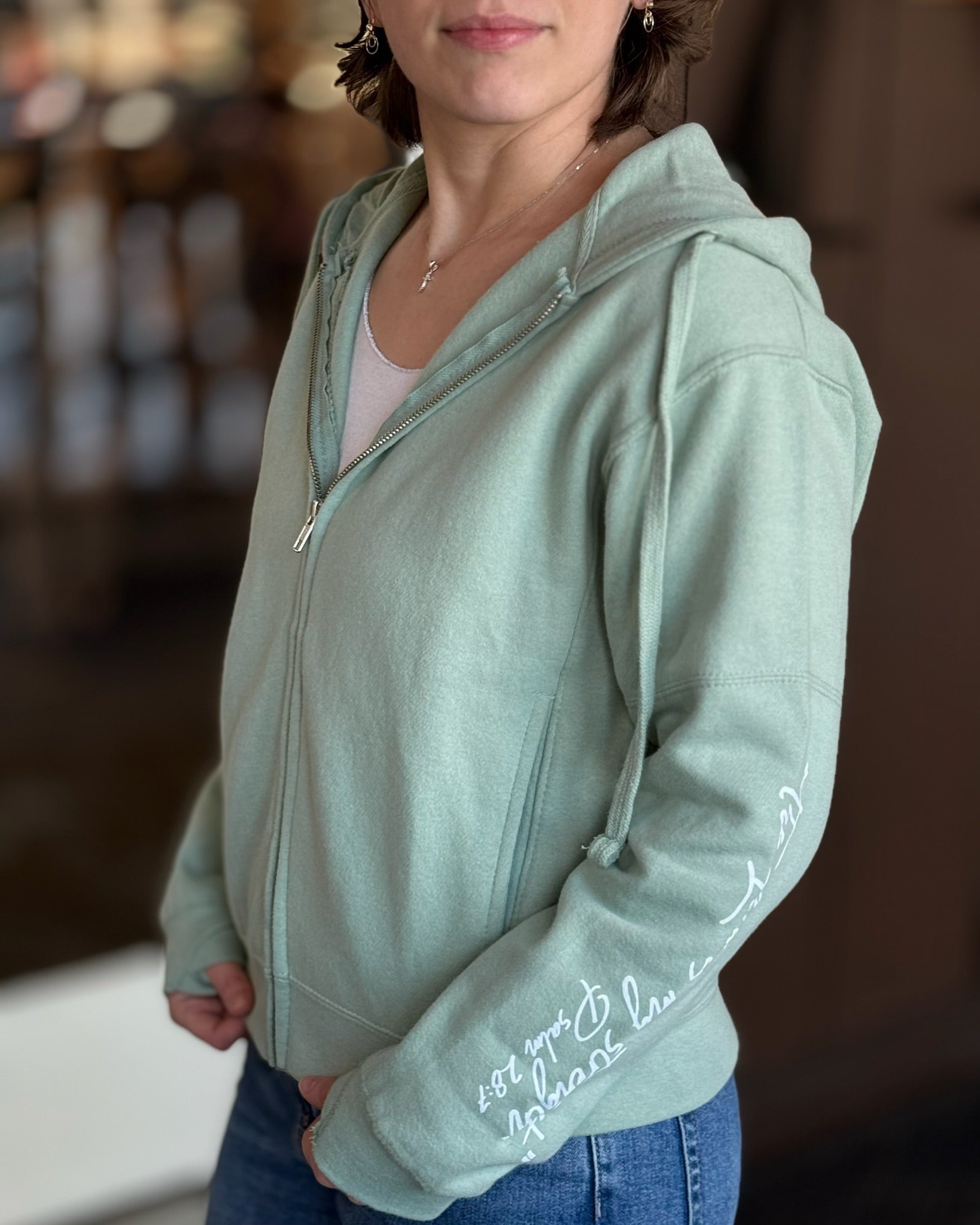 Woman wearing a sage green faith hoodie from Ardor Boutique 