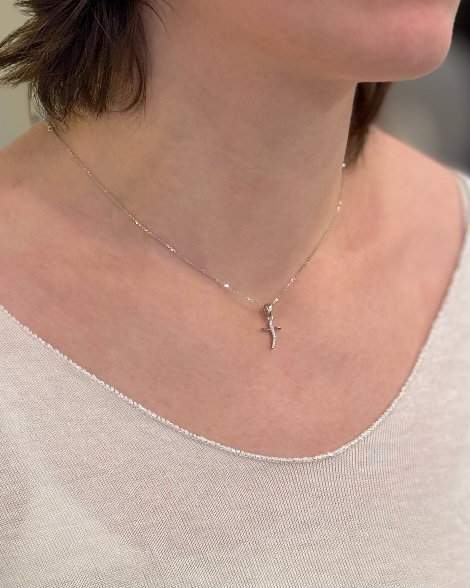 Necklace with a small pendant worn by a person against a neutral background