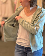 Shwood sunglasses shown inside the pockets of a strength faith hoodie