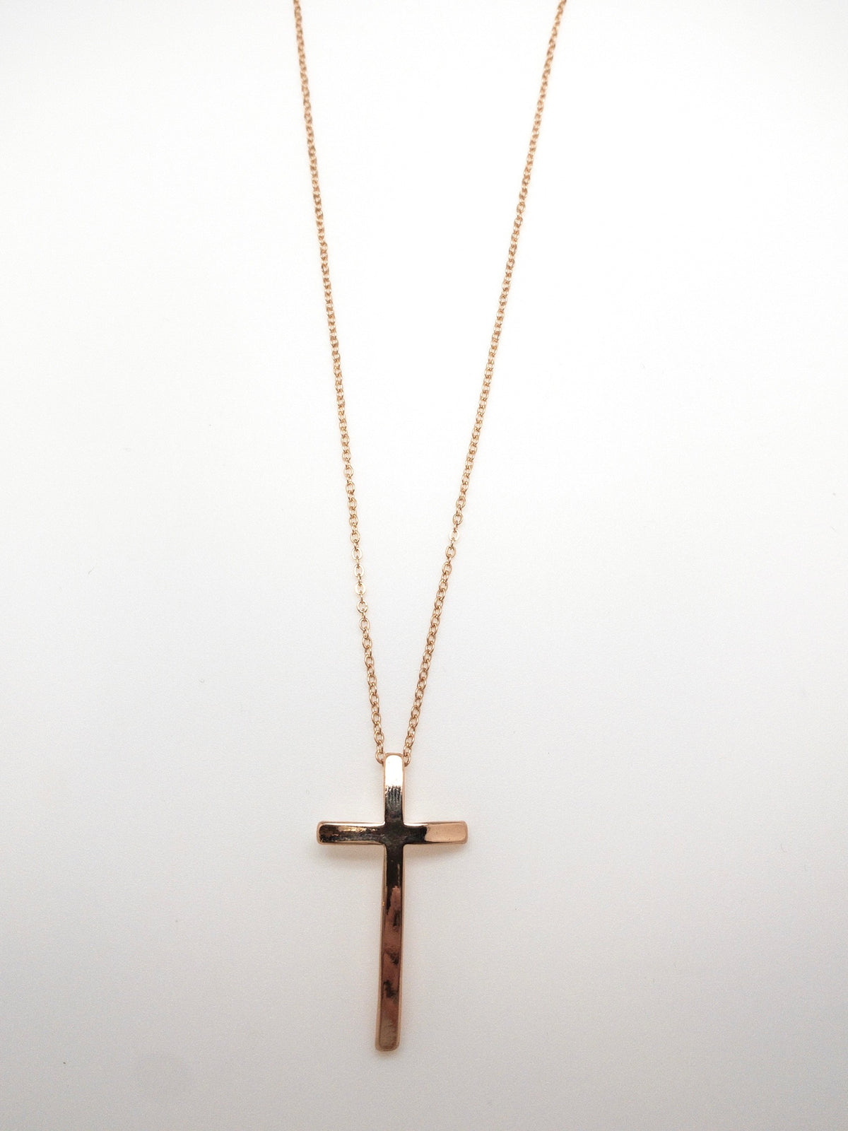 Gold-plated curved cross necklace with a delicate gold chain and slender cross pendant at Ardor Boutique.