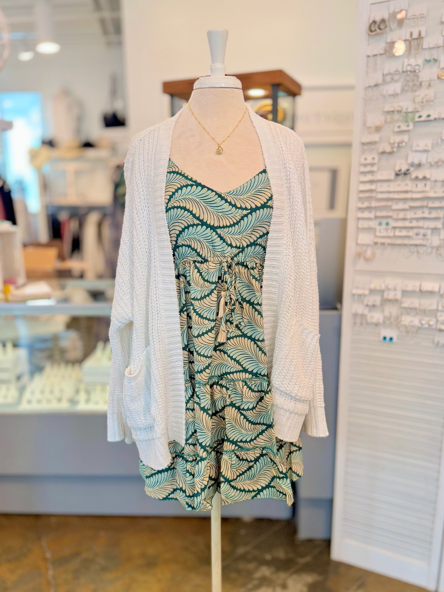 The Trina Dress in Tropical Green styled with cozy white knit cardigan and gold necklace for a layered spring look 