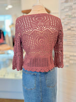 red crochet top on a mannequin with a blurred indoor background