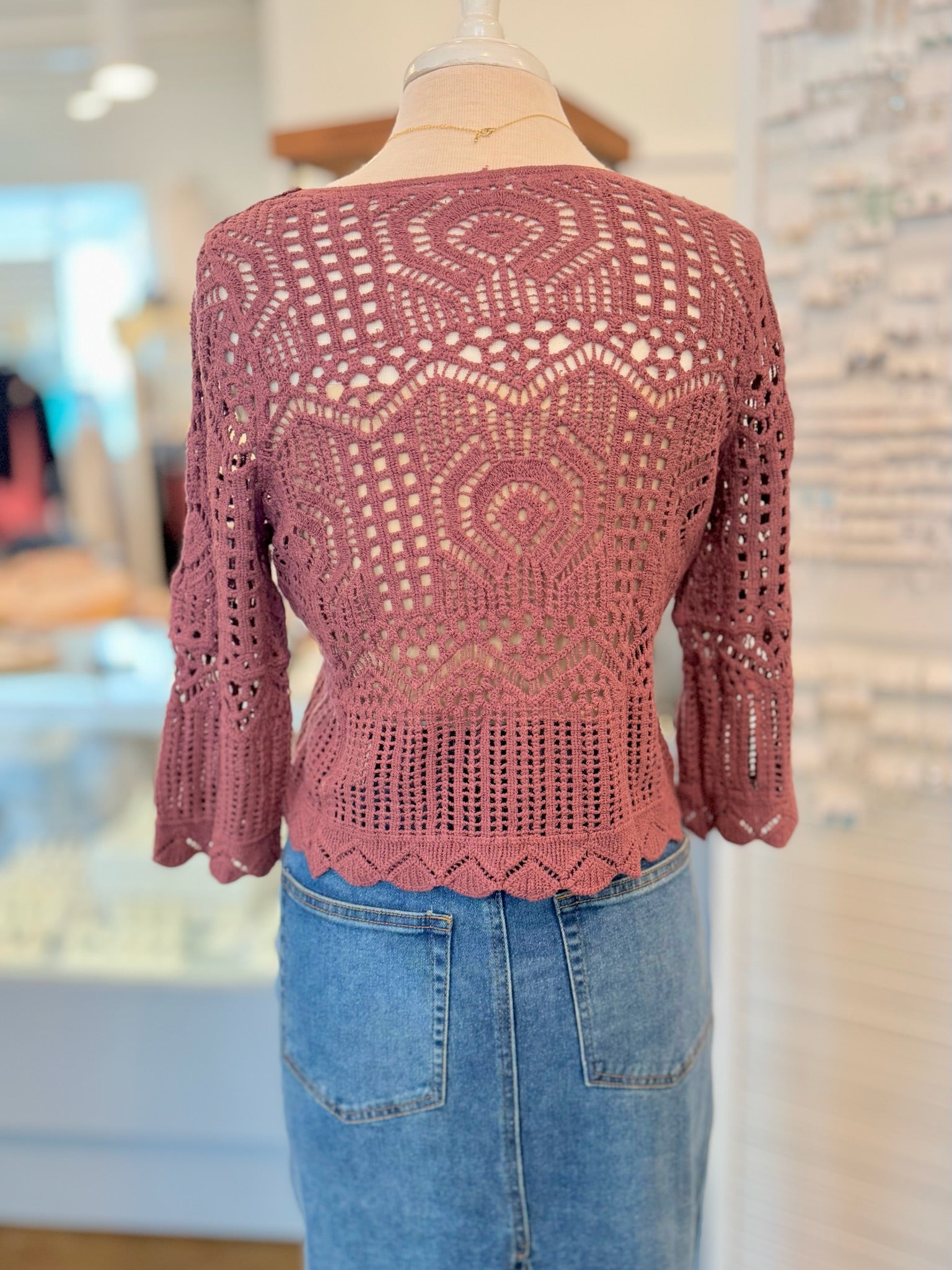 red crochet top on a mannequin with a blurred indoor background