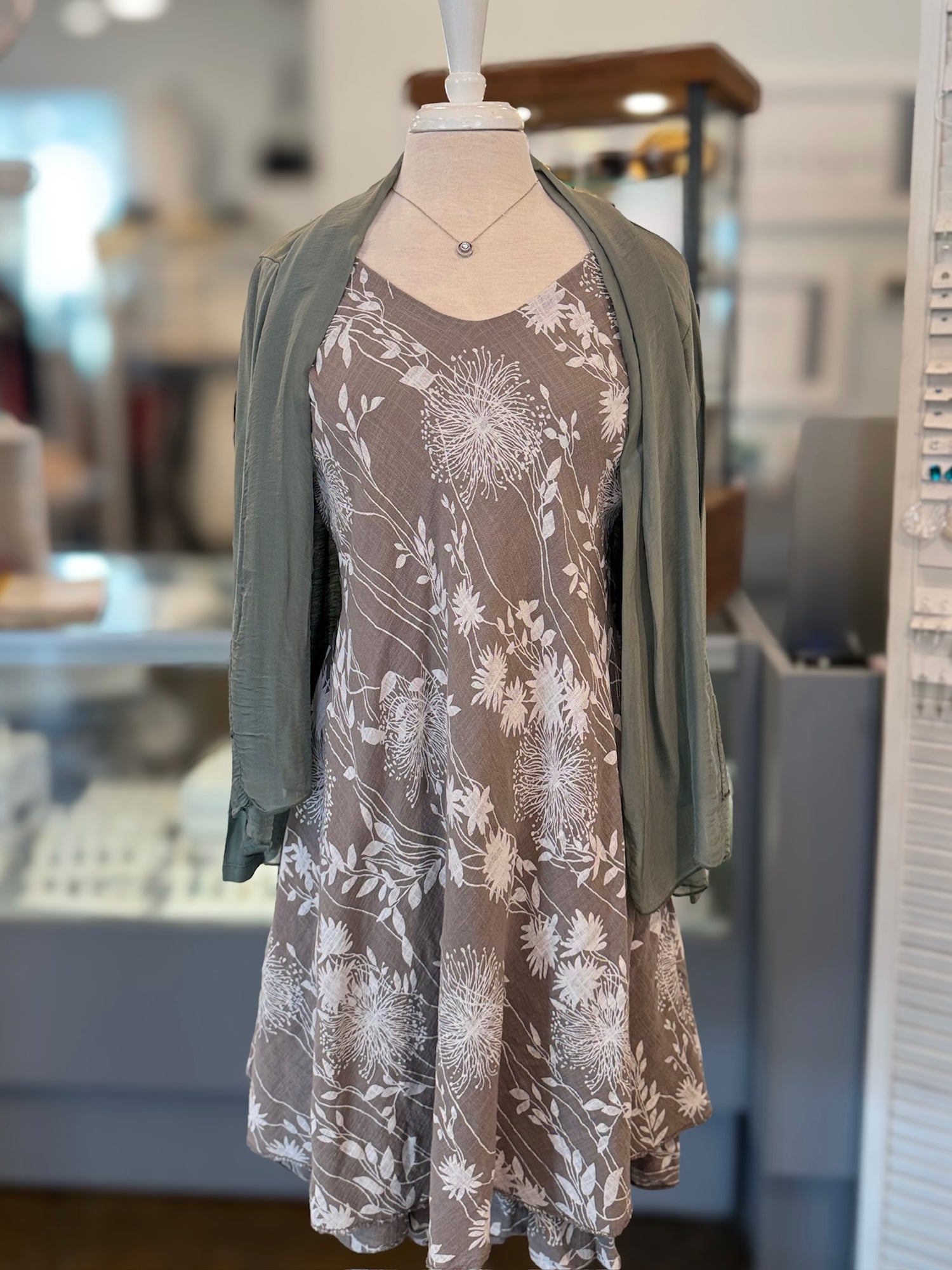 Floral dress with green cardigan on a mannequin in a store setting