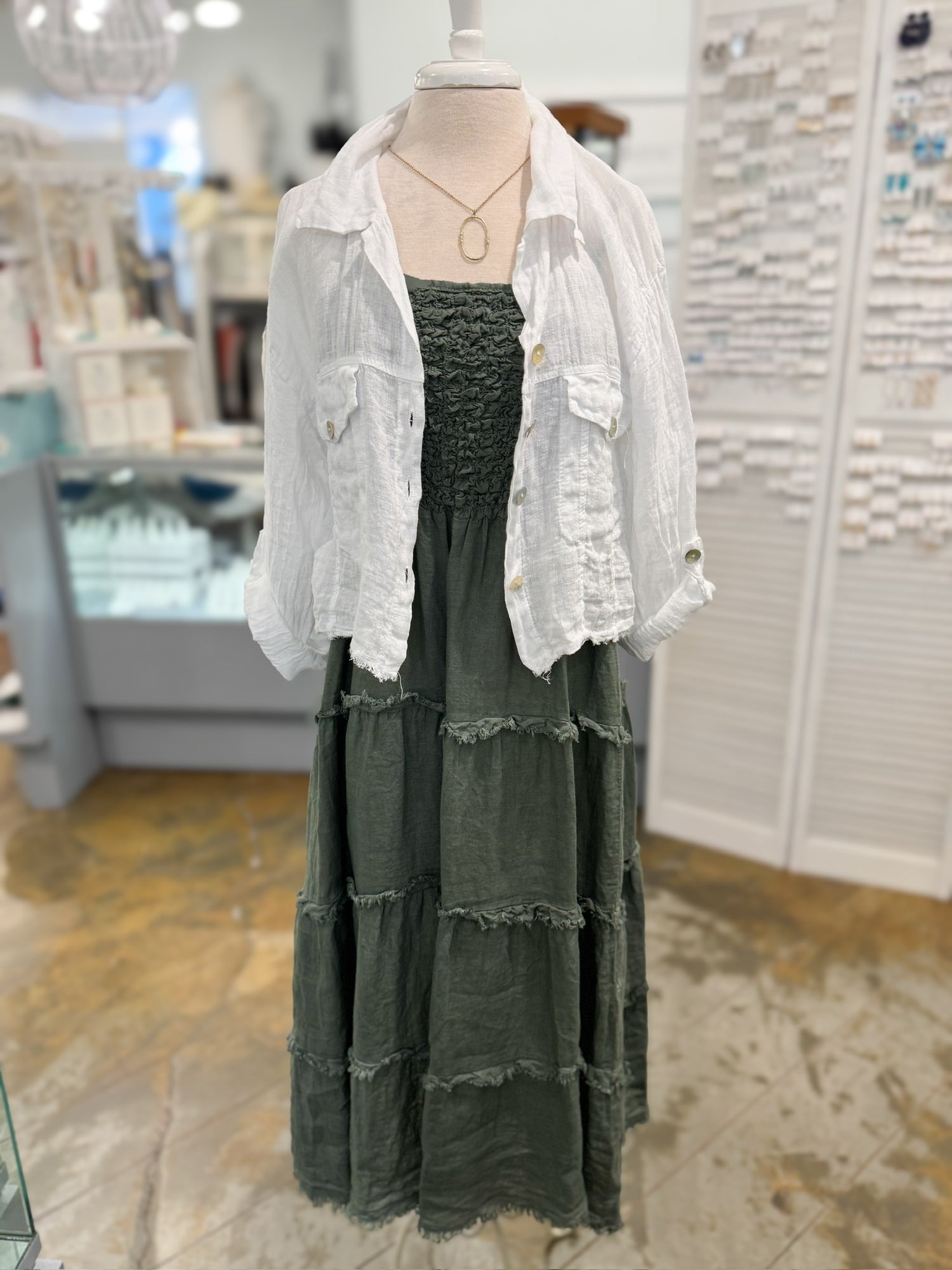 Green dress with a white jacket on a mannequin in a store setting