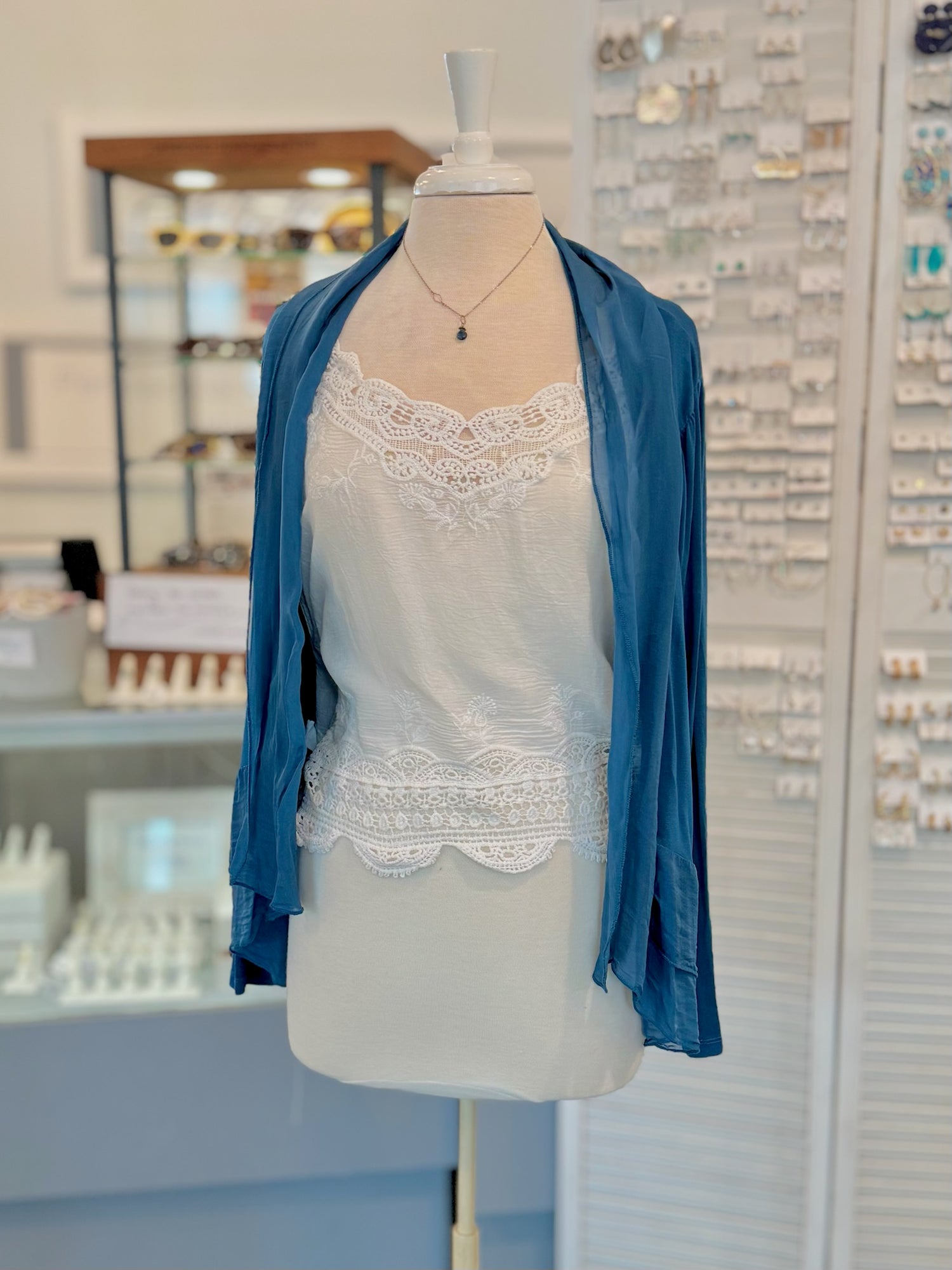 Mannequin wearing a blue cardigan over a white lace top in a store setting