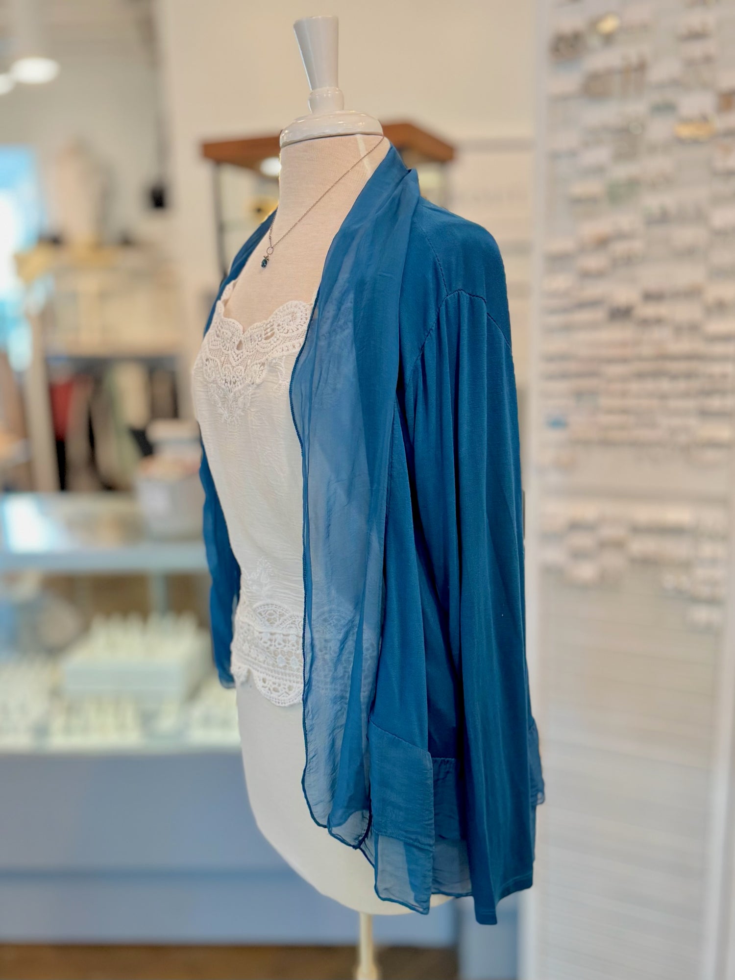 Blue sheer top on a mannequin with a blurred store interior background