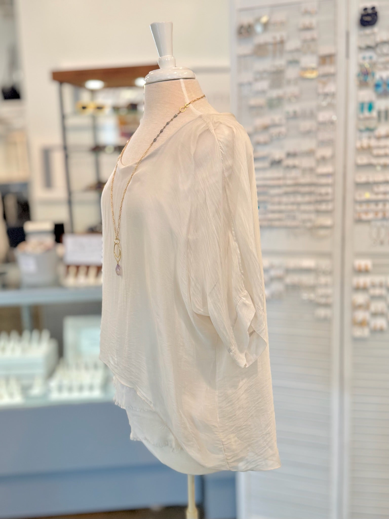 Beige blouse on a mannequin in a store setting