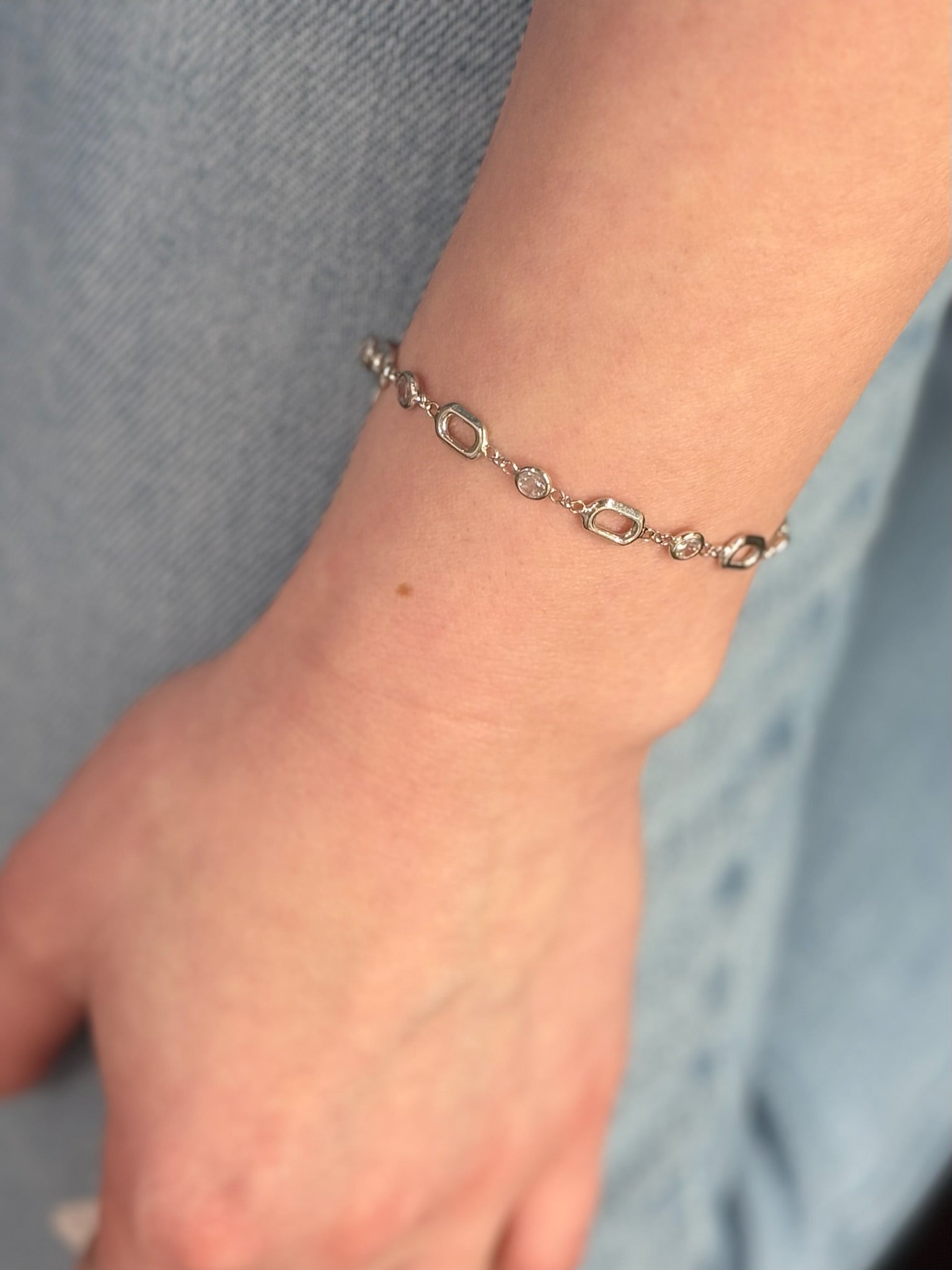 Silver bracelet on a wrist with a neutral background