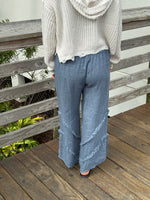 Back view of blue-gray linen pants featuring soft textured seams and a relaxed fit.