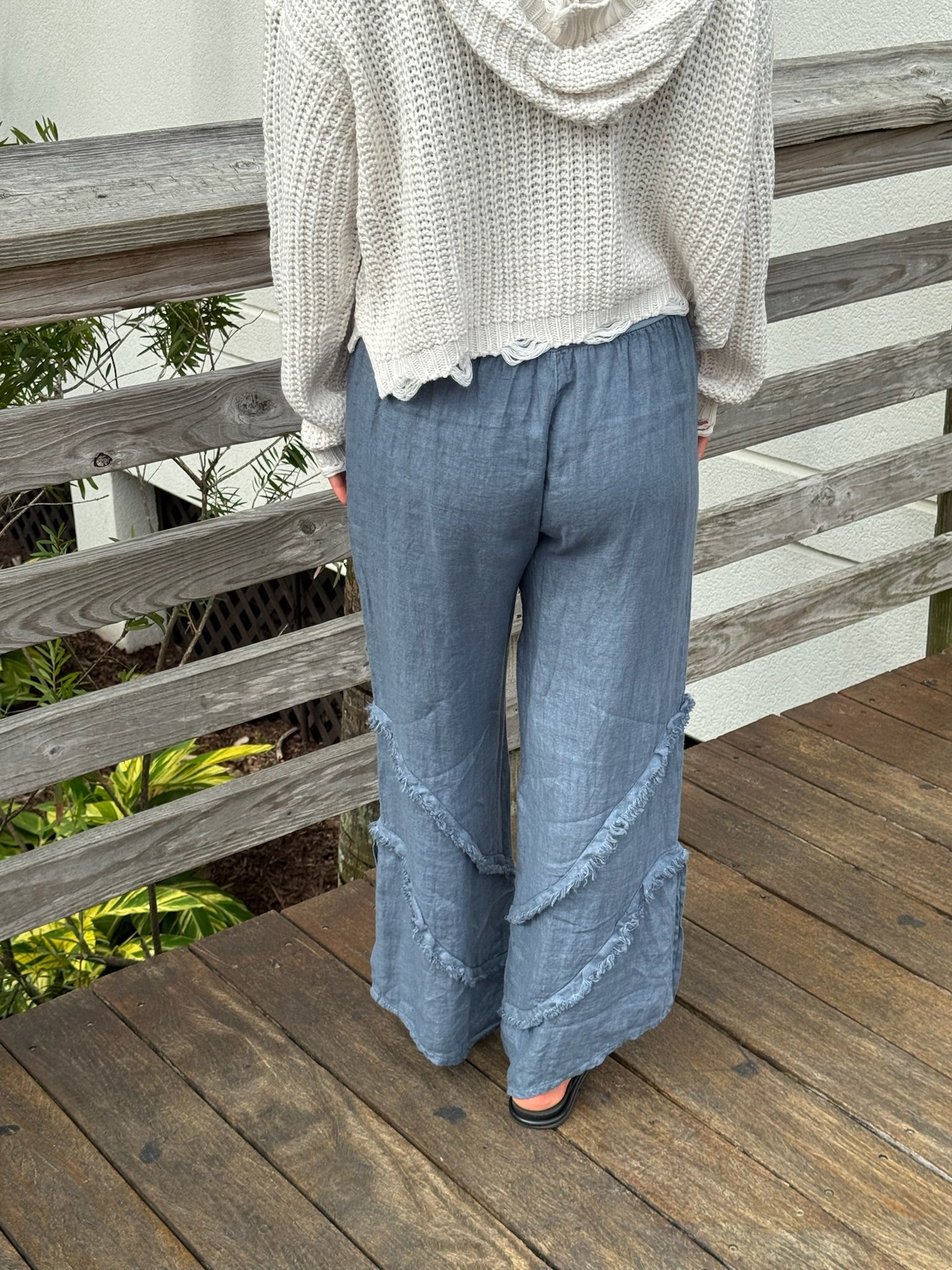Back view of blue-gray linen pants featuring soft textured seams and a relaxed fit.