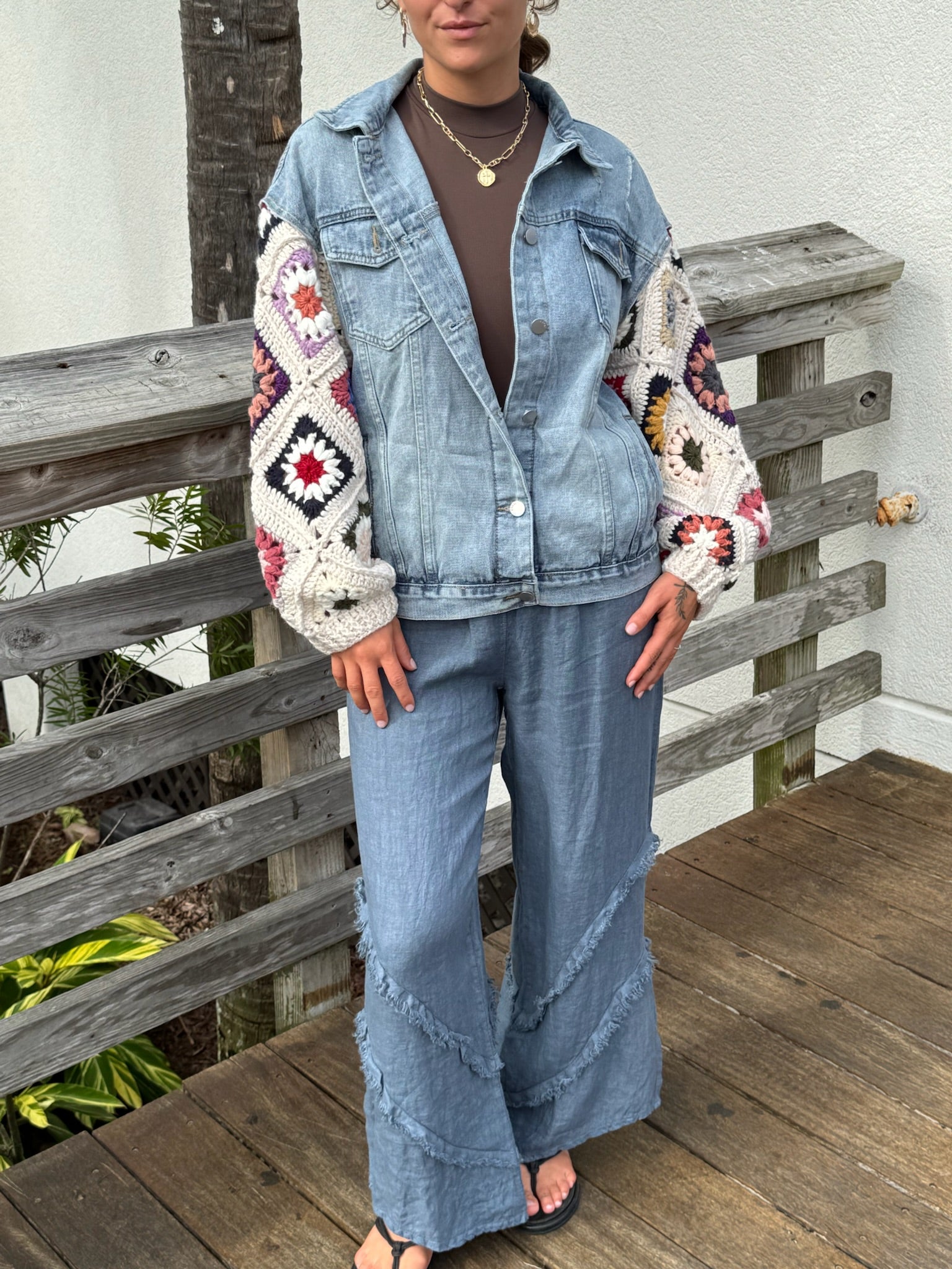 Model wearing A light-wash denim jacket with colorful crocheted sunset sleeves.