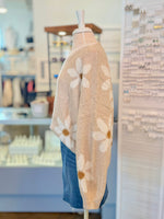 Side view of mannequin wearing a beige sweater with floral patterns and blue denim skirt in an indoor setting.