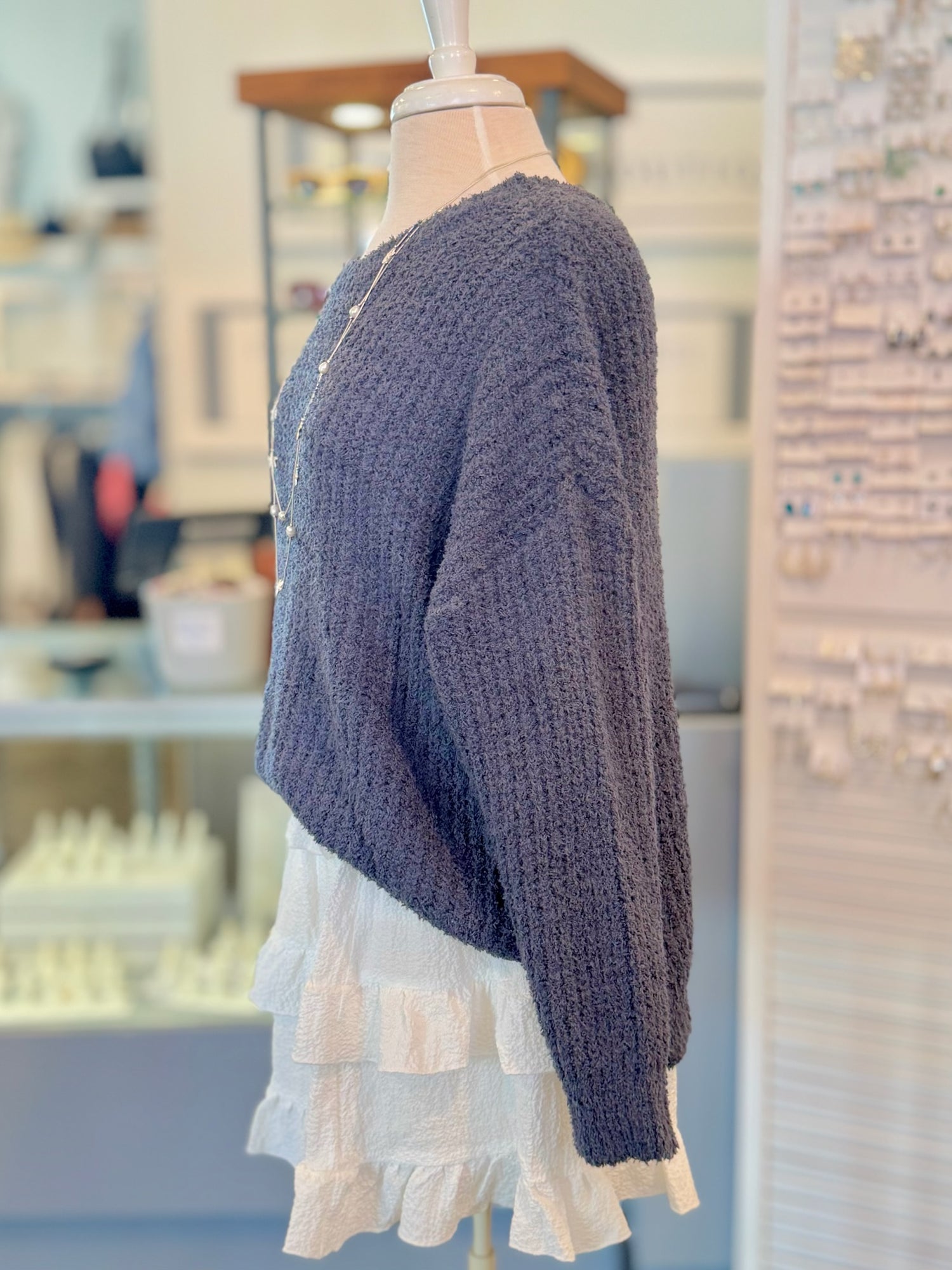 Blue knitted sweater on a mannequin with a blurred store background