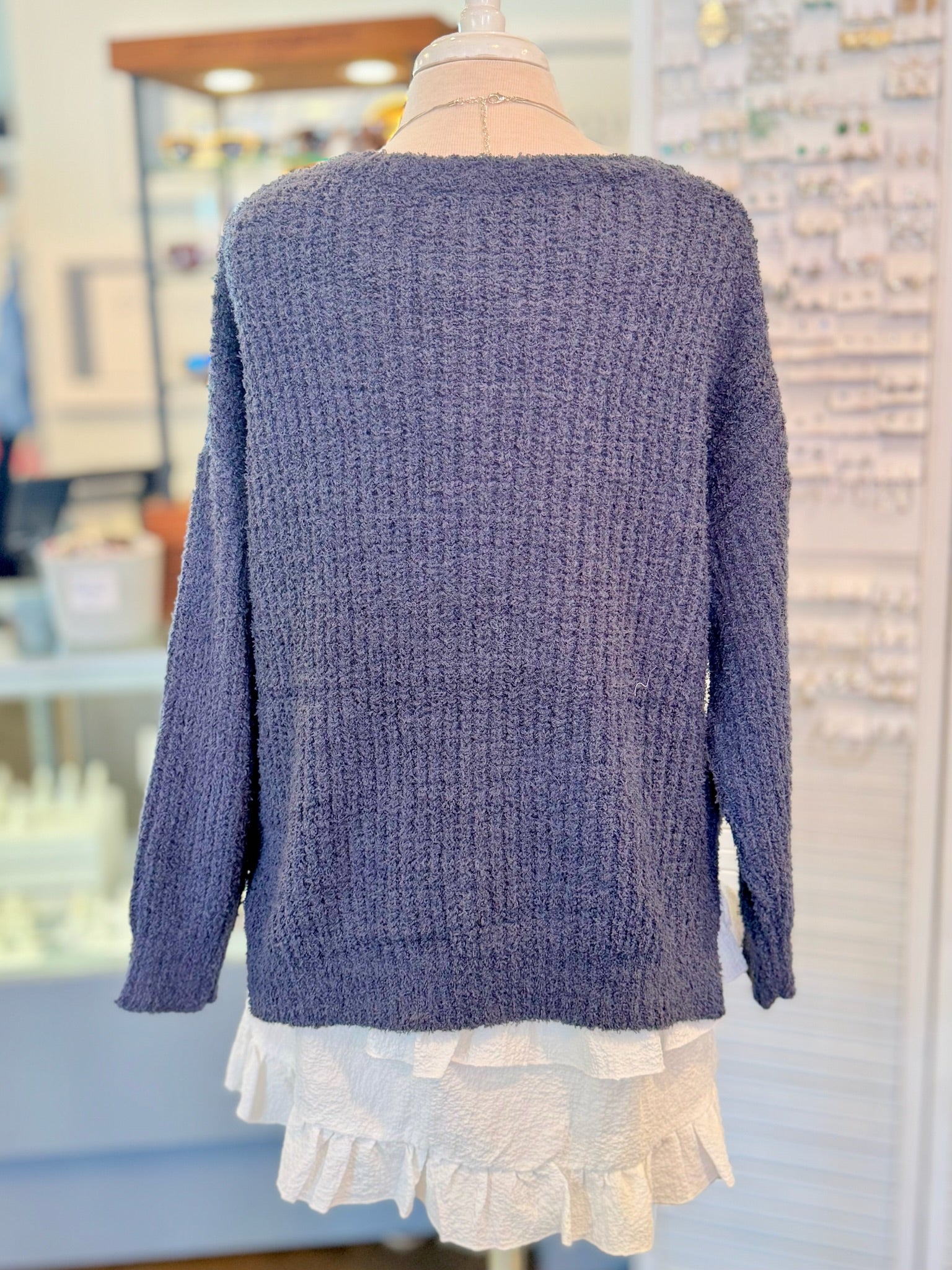 Blue knitted sweater on a mannequin with a blurred store background