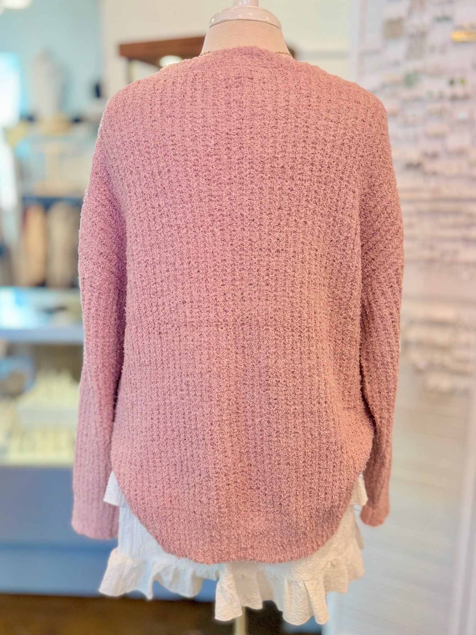 Mannequin wearing a pink sweater and white ruffle skirt in a store setting