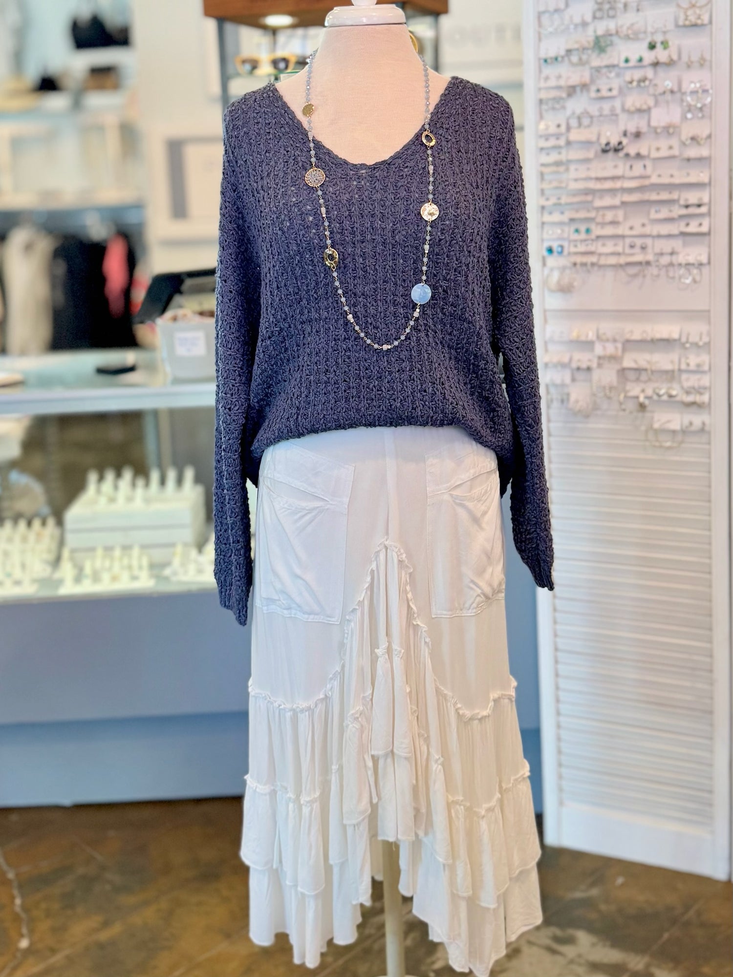 Mannequin wearing a navy sweater and white skirt in a store setting