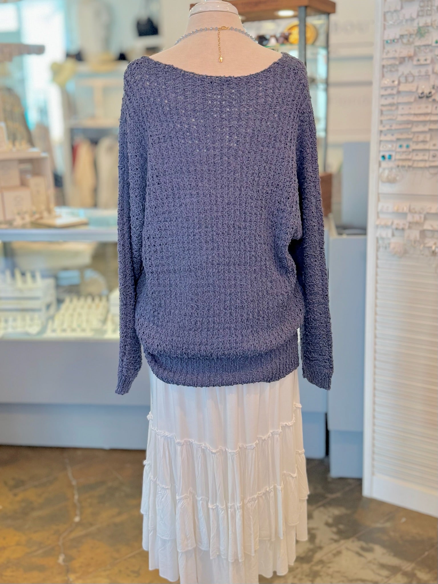 Mannequin wearing a navy sweater and white skirt in a store setting