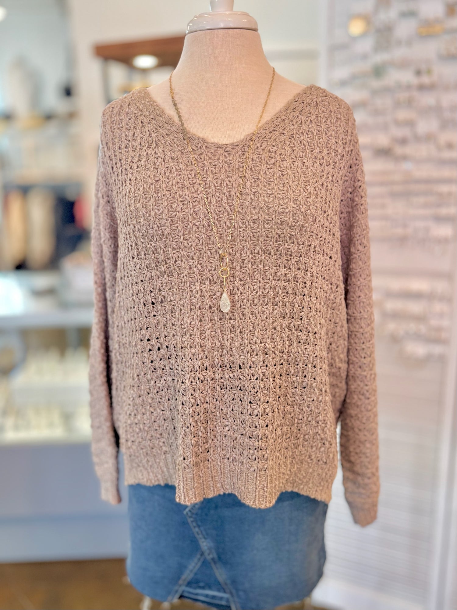 Beige knitted sweater on a mannequin with a blurred store interior background