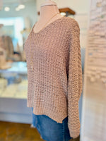 beige knitted sweater on a mannequin in a store setting side view