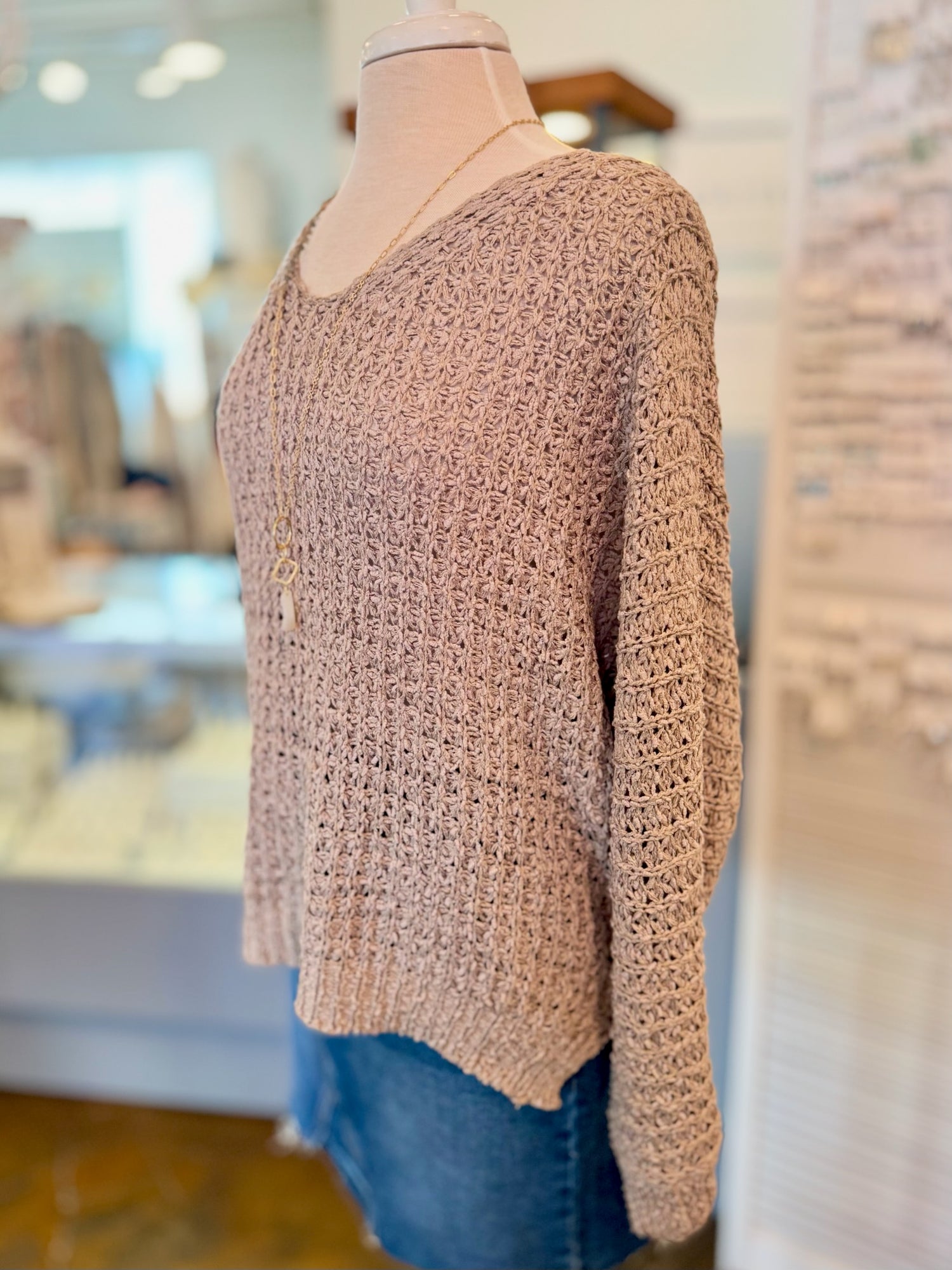 beige knitted sweater on a mannequin in a store setting side view