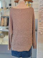 Beige knitted sweater on a mannequin with a blurred indoor background back view