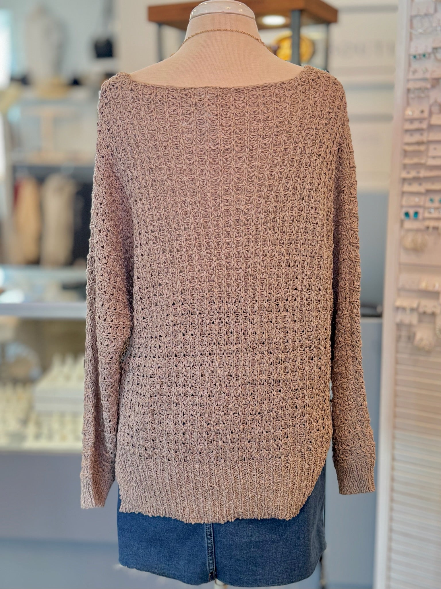 Beige knitted sweater on a mannequin with a blurred indoor background back view