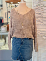 Mannequin wearing a brown knitted sweater tucked in and blue jean skirt in a store setting