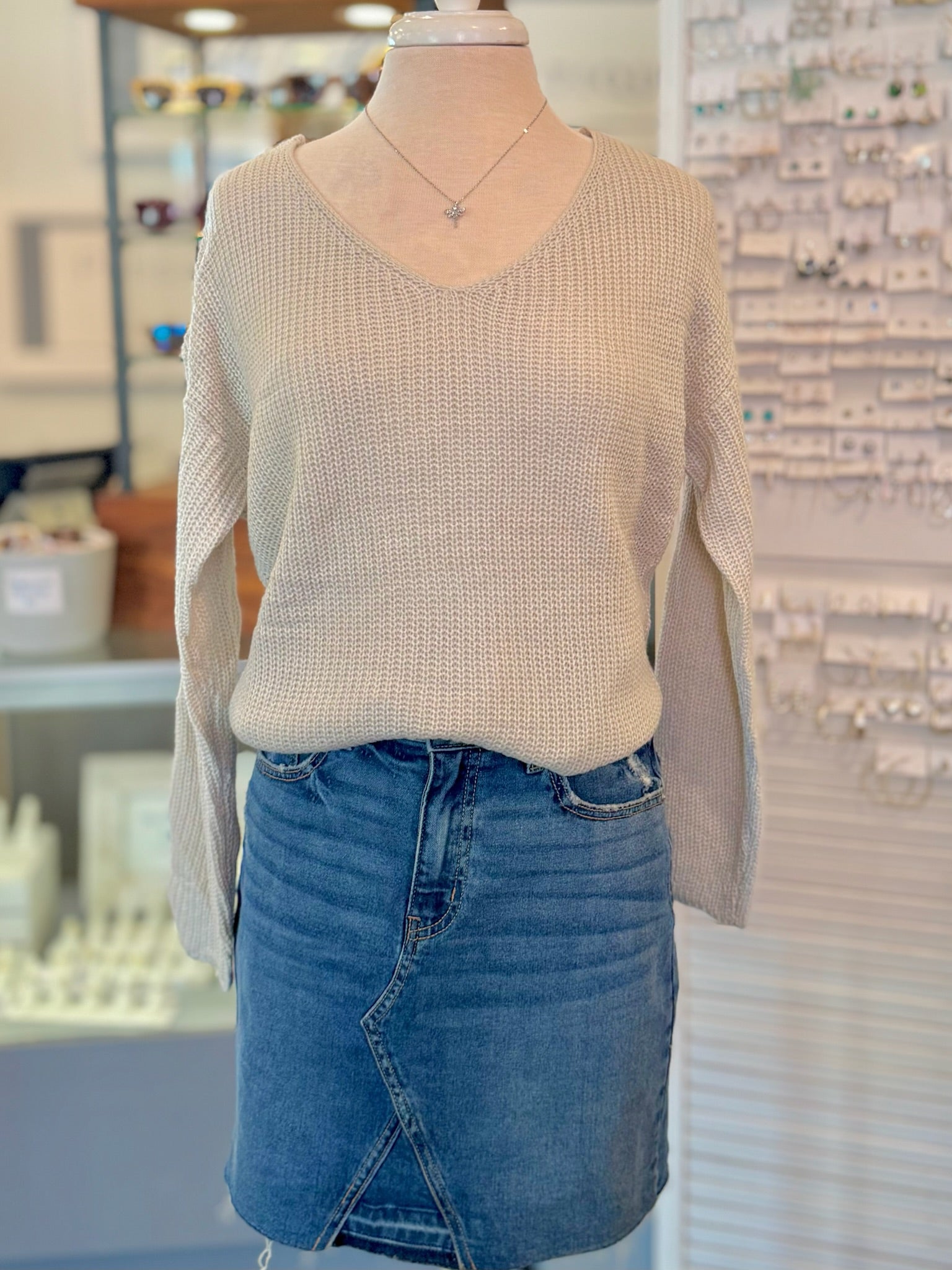Mannequin wearing a beige sweater and blue denim skirt in a store setting