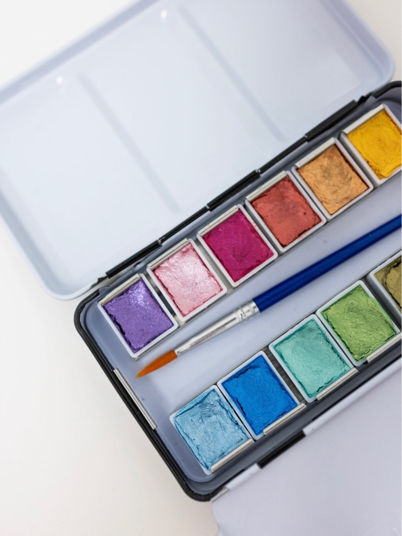 Watercolor paint set with a brush on a light background