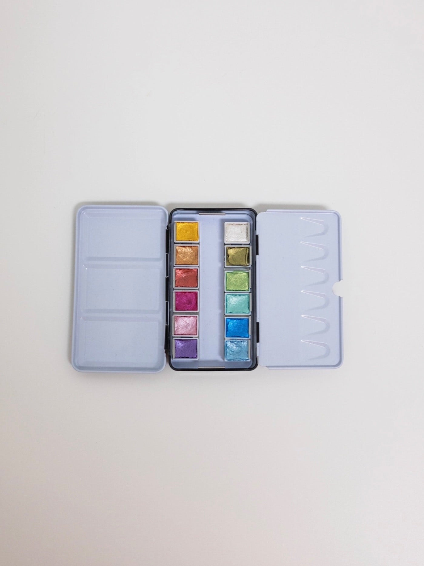 Set of watercolor paints in a portable case on a light gray background