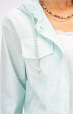 Close-up of seafoam hooded jacket featuring front patch pockets, wooden buttons, and adjustable drawstring hood